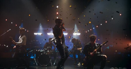 Indie Rock Band Delivers a Beautiful Live Performance With Guitars and Drums at a Modern Nightclub with Glittering Confetti. Colorful Lights and Powerful Sound at a Rock Festival