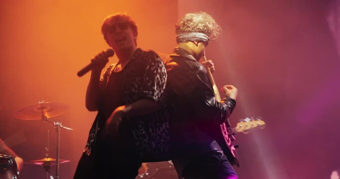 Stylish Lead Singer Performing Live on Stage with an Indie Band, Playing Alternative Music at a Rock Club. Animated Screen Compliments Intense Guitar Riffs at a Rock Concert on Festival Stage
