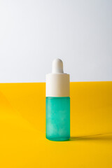 Blue glass cosmetic bottle, Skin care or sunscreen cosmetic with stylish props on white and yellow background.