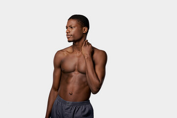 A muscular African American man, shirtless, poses confidently in a studio with a white background for a beauty routine.