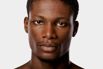 Obraz premium Close-up shot of an African American man showcasing his beauty routine in a studio with a white backdrop.