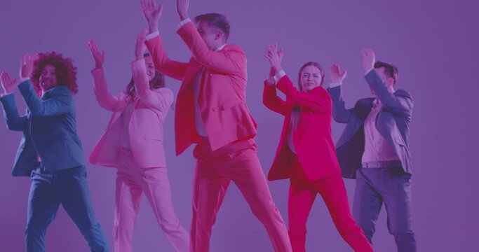 Group of dancers at fun disco party in club. Slow mo five happy, smiling, young people wearing pink, red, blue suits dancing together in flickering illumination on purple colour studio background