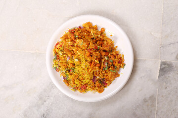 Bhel Puri is a savoury snack/Chaat item from India. It is made of puffed rice, vegetables & tangy tamarind sauce. Popular road side food. Served in bowl / plate over moody background. Selective focus