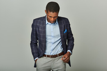 Handsome African American businessman in checkered blazer gazes downward thoughtfully.