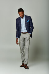 A stylish African American man stands confidently in formal attire against a clean white backdrop.