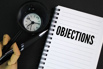 hands, a magnifying glass, an alarm clock and a book with the word Objections