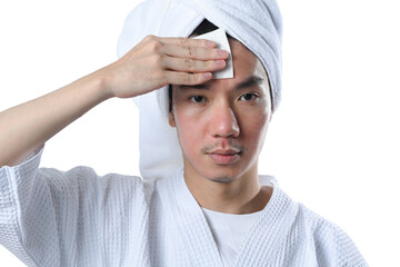 Young man cleaning his face using cotton pads and cleansing product. Skin care and cosmetic...