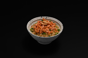 Tasty Japanese fried rice or Yakimeshi topped with salmon and spring onion on black background