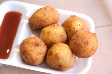 Batata vada or Aloo bonda is tasty,spicy and popular streetfood of India,Maharashtra,served with red chutney / sauce. selective focus