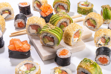 Creative  Japanese seafood sushi set background containing sushi rolls, maki, gunkans with chopsticks on white table