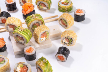 Creative  Japanese seafood sushi set background containing sushi rolls, maki, gunkans with chopsticks on white table