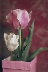 Two pink tulips in a pink vase on a table, suitable for home decor or romantic settings