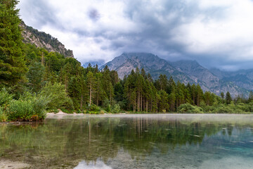 A serene landscape showcasing the Almsee Lake nestled amidst a lush forest, with towering Austrian...