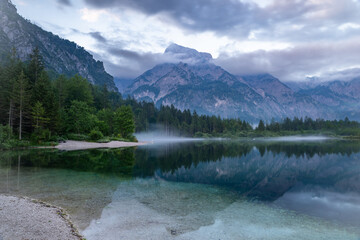 This stunning image captures the beauty of Almsee Lake in Austria. The calm waters reflect the surrounding mountain peaks, creating a breathtaking scene. 