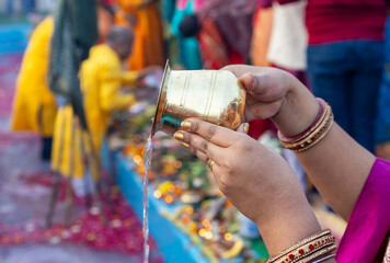 holy water offerings by indian devotee doing traditional rituals at chhath festival at morning