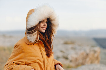 Fashionable woman in orange parka with fur hood looking at camera in winter outdoor setting