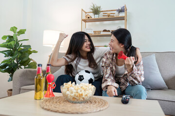 Happy LGBT Lesbian Couple Cheering for Sports Team at Home, Celebrating Victory, Watching Game on TV, Excitement and Joyful Moments Together
