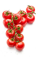 Two sprigs of ripe cherry tomatoes on a white wooden surface. Close-up of cherry tomatoes. Vertical orientation of the photo.