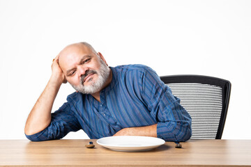 Concept showing Indian asian retired senior old man with empty ceramic plate, holding, presenting or pointing