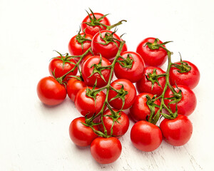 Ripe cherry tomatoes with water drops on white wooden background, top view.