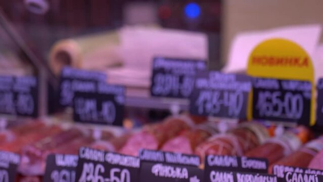 Sumy, Ukraine - December 21, 2023: Meat products store. Sausages on display at a grocery store. Sausage price tags.