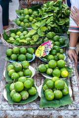 Lots of lemons tied into packages on plates on a market stall.