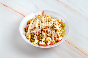 Fresh Caesar Salad with Bacon and Creamy Dressing on a Marble Background