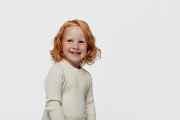 Redhaired girl in white sweater standing against white background as symbol of innocence and beauty