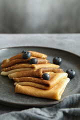 Russian pancakes served on dark grey plate with grey background 