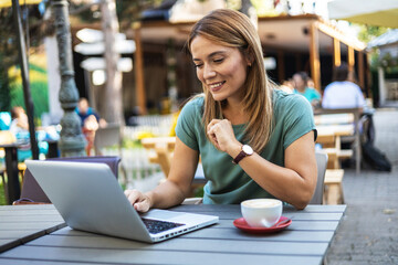 Beautiful smiling Caucasian woman using laptop at the bar.