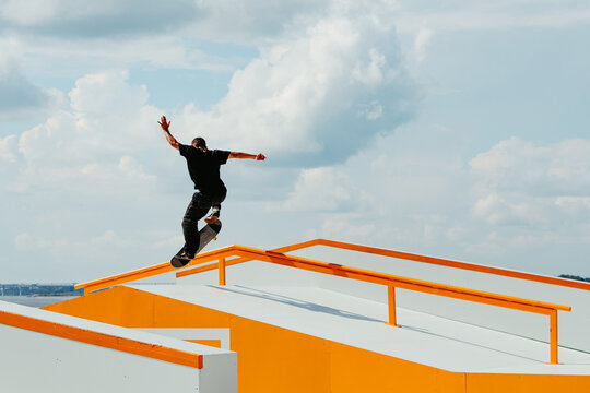 atino Boy doing skateboard trick on rail in skatepark. Professional sportsman grinding on skateboard in outdoor park. Faceless unrecognizable Latin skater doing Manual Grind trick. Skate background - Powered by Adobe