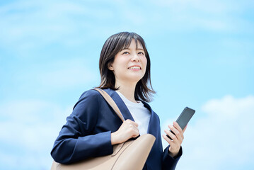 スマートフォンを手に出勤する若い女性