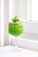 Refreshing mocktail made from green apple, mint, and lemonade; copy space on a white window ledge; copy space