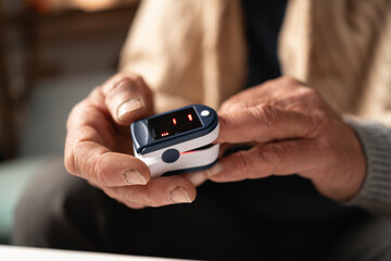 Senior man using pulse oximeter, close-up of hands monitoring oxygen levels