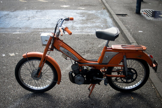 Mulhouse - France - 9 June 2024 - profile view of orange motobecane motorbike parked in the street