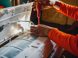 Hand of technician use a screwdriver to tighten the air conditioning assembly nuts, Air conditioning technicians Prepare to  install new air conditioner in homes.