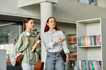 A redhead woman teaches a teenage girl in a library, engrossed in books