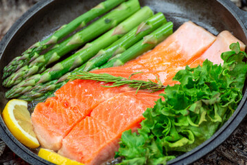 Healthy baked salmon steaks with greens and asparagus in a black cast iron skillet. A delicious low-carb breakfast.