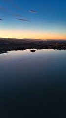 Beautiful yellow orange reddish sunset at dusk stretching over a lake in which slight reflections are visible