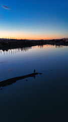 Beautiful yellow orange reddish sunset at dusk stretching over a lake in which slight reflections are visible