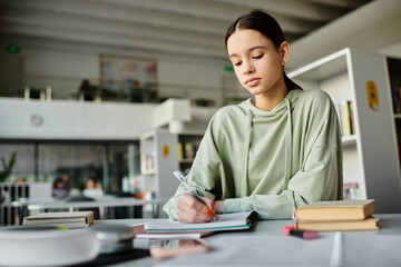 A teenage girl engaged in writing notes in a notebook while sitting at a desk, absorbed in her studies.