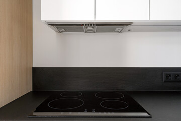 Electrical stove and extractor hood at kitchen with modern interior
