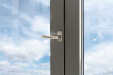 Pvc window with silver handle and view on blue sky through transparent glass