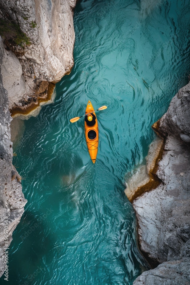 Wall mural A person is seen paddling a yellow kayak down a river