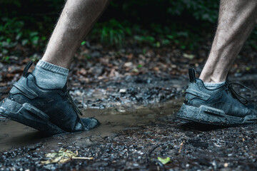 Wide close up shot of a male runner running on the nature muddy trail