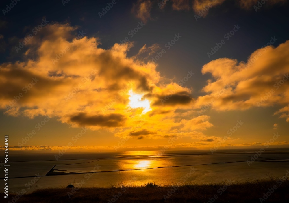 Canvas Prints Stunning sunset over a calm ocean with golden clouds in the sky