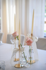 Festive table covered tablecloth, decorated composition flowers and candles in party area. Wedding setup detail. Table setting, serving closeup. Banquet decoration in hall. Luxury reception. Side view