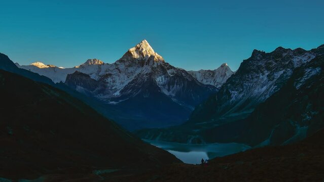 Scenery Ama dablam mountain peak and Chola lake. View from Dzongla village.Couple hikers by Dzongla village explore Himalayas. Everest base camp trek.Sagarmatha national park