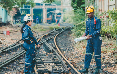 Engineer in safety gear inspects railway track for wear and alignment, ensuring safety standards.