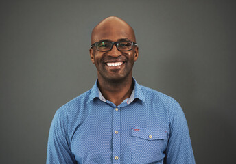 Obraz premium Smile, entrepreneur or portrait of black man in studio with pride, business and confidence for fashion. Startup, person or happy African designer with shirt or glasses isolated on grey background